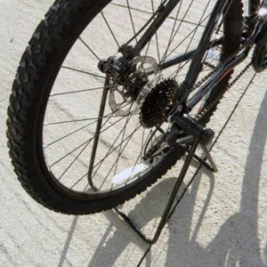 Gedetailleerd close-up van de stevige metalen fietsstandaard die het achterwiel stabiel ondersteunt.