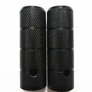 Close-up detail of black steel bicycle stunt pegs featuring anti-slip knurled pattern.