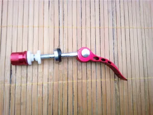 Detailed shot of red aluminum alloy bicycle quick release seatpost skewer component hardware.