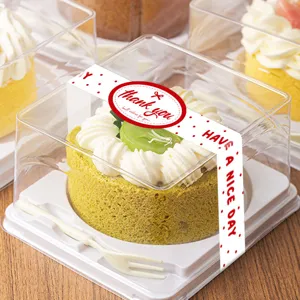 Transparent square cake box detail with sealing sticker, fork and green roll cake.