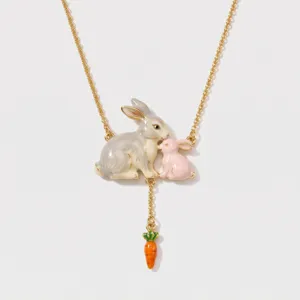 Close-up detail of the cute enamel bunny and carrot pendant necklace with gold chain finish.