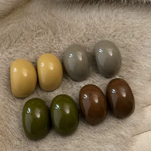 Close-up detail of glossy earth-tone pebble shaped stud earrings in brown and green.