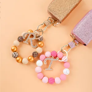 Estuche llavero de cuero con purpurina, pulsera de cuentas y abalorios de letras.