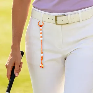 Close-up detail of colorful beaded golf stroke counter hanging on white trousers belt loop.