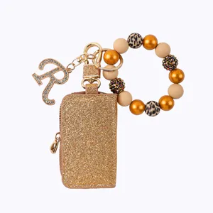 Estuche llavero de purpurina dorada con pulsera de cuentas y abalorio letra R vista principal