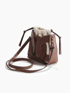 Vista dettagliata della borsa a secchiello in pelle marrone con sacca interna in tela beige.