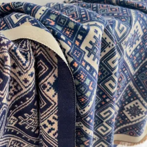 Detail of geometric jacquard shawl fabric, showing intricate woven patterns and soft touch.