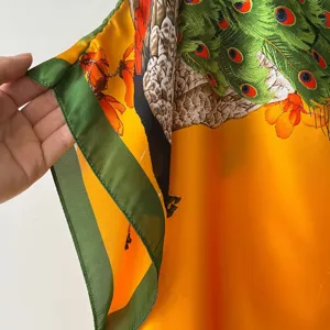 Vibrant peacock print silk scarf featuring elegant green and orange hues, perfect for summer.