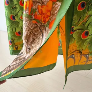 Detailed close-up of vibrant peacock feather and floral print silk scarf fabric texture.