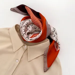 Detailed view of women's silk square scarf with trendy crescent moon print and chic color block.