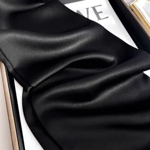 Gros plan d'un foulard en soie noire luxueux montrant une texture délicate et plis.