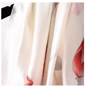 Primer plano detalle de bufanda de seda elegante para mujer con estampado de loto rojo suave.