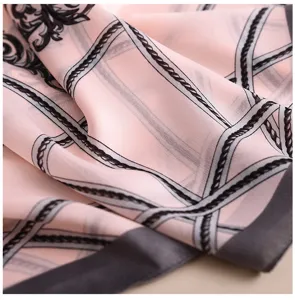Vista ravvicinata di dettaglio di un foulard in seta rosa con elegante motivo a catena.