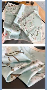 Detailed view of a light green silk small square scarf with elegant white magnolia flower print.