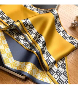 Vue détaillée de l'écharpe en soie jaune et grise élégante avec un motif de lettres.