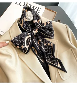 Close-up detail of a luxurious black and beige monogram silk scarf tied neatly on a blazer lapel.