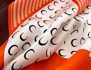 Detailed close-up view of a silk square scarf featuring a distinctive crescent moon pattern.