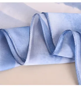 Close-up of blue gradient silk scarf fabric, showing fine stitching and smooth texture.