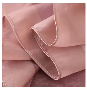 Close-up detail of soft pink imitation silk scarf fabric texture and delicate stitched hem.