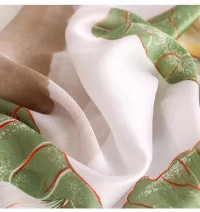 Close-up detail of smooth silk-like scarf featuring elegant green botanical leaf prints.
