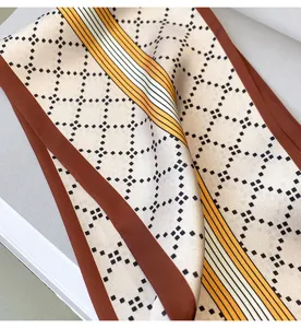 Primo piano dettagliato dell'elegante sciarpa lunga e sottile con motivo a losanghe geometriche.