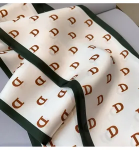 Close-up detail of the fashion silk scarf featuring stylish letter print and contrast dark green border.