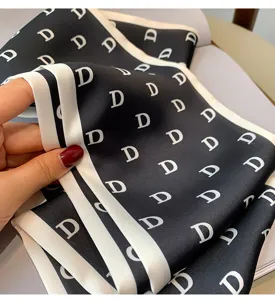 Detailed view of black and white letter print silk scarf, elegant hair ribbon or bag accessory.