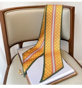 Vista dettagliata di un foulard in seta con motivo a losanghe gialle e bordi verdi chic.
