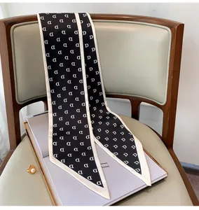 Detail view of a chic black and white skinny silk scarf with monogram D print on a chair.