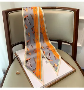 Vista dettagliata di un elegante foulard twilly in seta grigia e arancione con foglie.