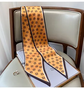 Vista dettagliata della sciarpa in seta arancione con stampa monogramma, elegante foulard.