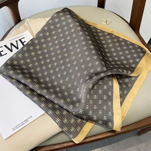 Silk scarf detail view, elegant grey and gold monogram pattern, chic luxury style accessory.