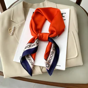 Vista dettagliata del foulard in seta sintetica arancione e blu scuro con stampa a catena.