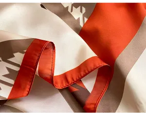 Silk scarf fabric detail close-up showing orange brown geometric chain print pattern.