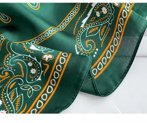 Detailed close-up of a green paisley pattern silk scarf, showing fine texture and neat stitching.