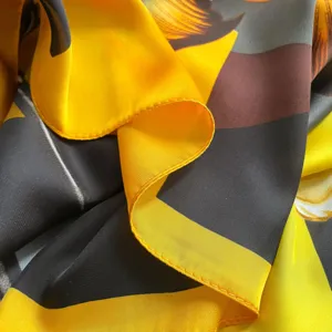 Primo piano dettagliato della texture del lussuoso foulard in seta gialla e nera orlo.