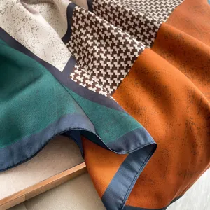 Close-up of chic color-block silk scarf shawl with geometric houndstooth and vibrant tones.