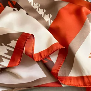 Close-up detailed texture view of women's orange geometric pattern long silk scarf fabric.