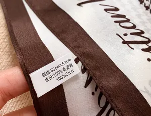 Close-up detail view of the 100% mulberry silk square scarf showcasing the product care label.