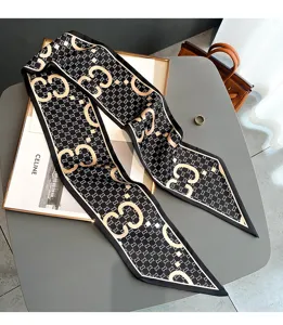 Detailed view of black silk-like skinny scarf with monogram pattern, elegant neckerchief.