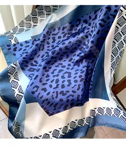 Vista dettagliata di un elegante foulard in seta blu con stampa leopardata e geometrica.