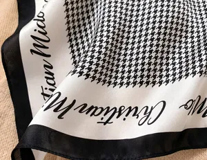 Close-up of black and white houndstooth silk square scarf, classic neckerchief detail.