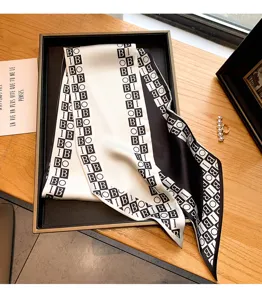 Vue détaillée du foulard étroit en soie imprimé en noir et blanc avec un design élégant.