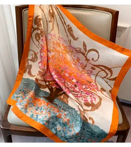 Elegante foulard in seta con una stampa floreale artistica e vivace bordo arancione.