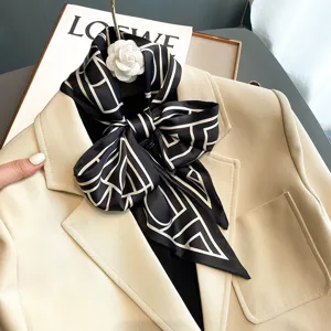 Chic black and white geometric silk scarf with elegant bow tie and white camellia brooch.