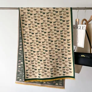 Vista dettagliata della sciarpa in cashmere con motivo di mucche e frange gialle.