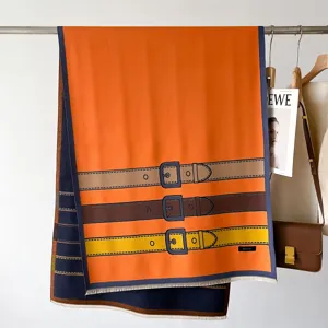 Detailed view of the orange winter scarf featuring a classic belt print and fringe.