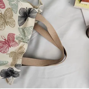 Canvas shoulder bag detail showing butterfly print and sturdy brown straps on fabric.