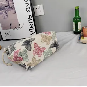 Canvas cosmetic pouch featuring a chic multi-color butterfly print and secure drawstring closure.
