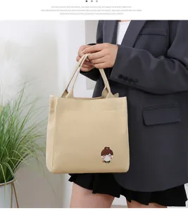 Detail view of cute canvas lunch tote bag in beige with cartoon graphic, lightweight use.
